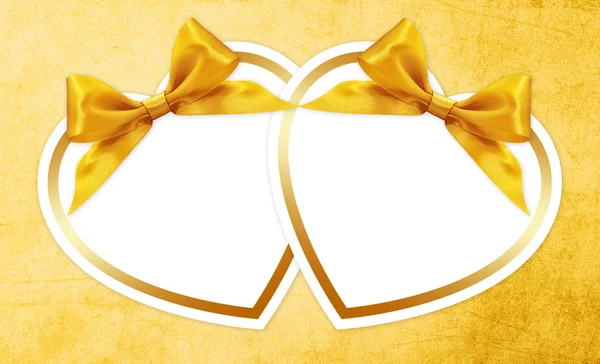 Shapes of hearts with golden ribbon  bow isolated on yellow back — Stock Photo, Image