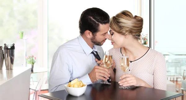 Casal amoroso beijando sentado em uma mesa com copos de vinho — Fotografia de Stock