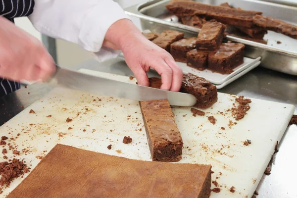 Šéfkuchař řezání čokoládové brownies — Stock fotografie