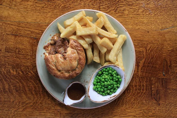 Steak and mushroom pie with chips and peas — Stock Photo, Image