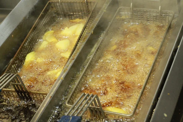 Batatas lascadas fritando em óleo quente — Fotografia de Stock