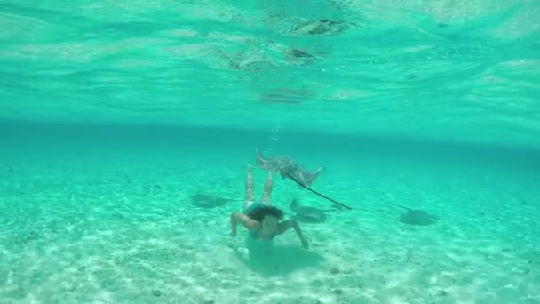SLOW MOTION: Nuori nainen uinti vedenalainen ystävällinen rausku säteet — kuvapankkivideo