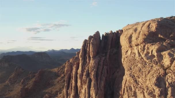 AERIAL: Flying pass rocky mountain top towards the desert valley — Stock Video