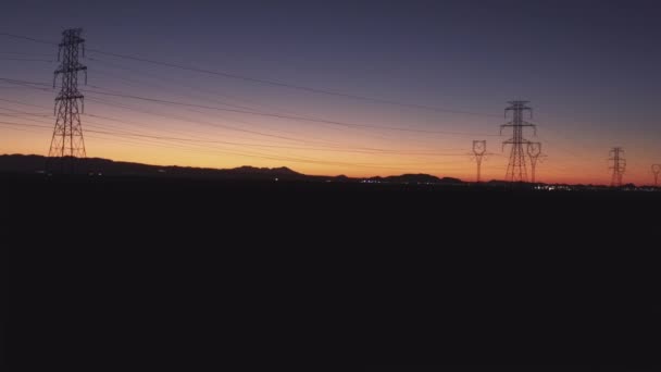 Antenne: Hoogspanning elektriciteit torens en elektrische leidingen bij zonsondergang — Stockvideo