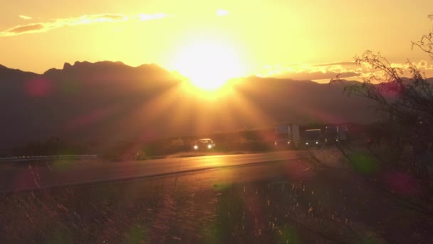 Cars and freight transporting trucks driving on busy highway at golden sunset Video Clip