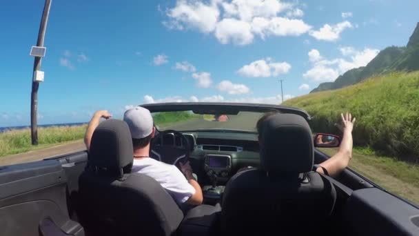 CERRAR: Feliz pareja joven conduciendo a lo largo de la carretera costera en coche convertible rojo — Vídeo de stock