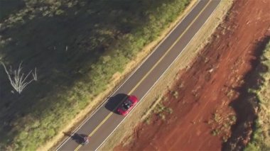 Aerial Close Up: Kırsal yol boyunca giden kırmızı cabrio araba üzerinde uçan