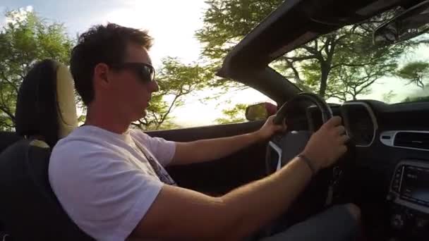 CHIUSURA: Felice uomo in cabriolet guida lungo la strada costiera, ascoltando musica — Video Stock