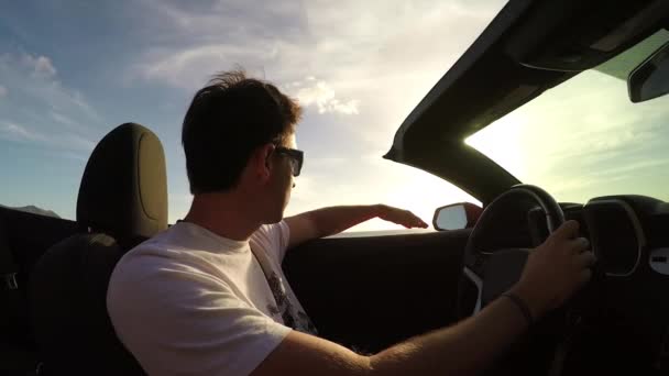 FECHAR UP: Homem alegre dirigindo em cabriolet de luxo, ouvindo música e dançando — Vídeo de Stock