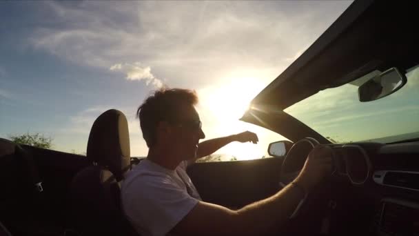Close-up: opgewonden jonge man genietend van het strand rijden in cabriolet bij zonsondergang — Stockvideo