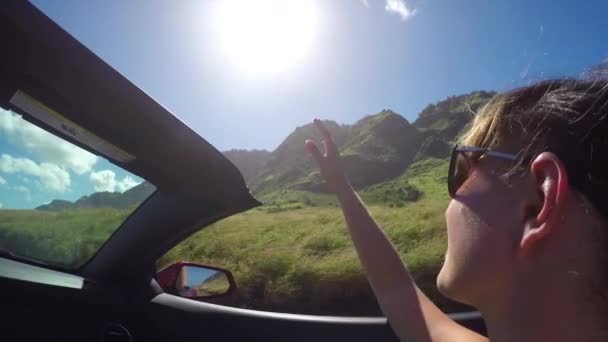 FECHAR UP: Mulher feliz dirigindo através da natureza havaiana brincando com o vento no verão — Vídeo de Stock