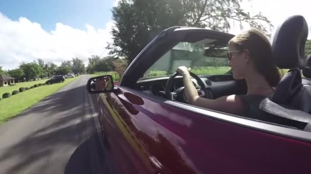 スローモーション:ハワイの村を通って赤いコンバーチブル運転の若い女性 — ストック動画