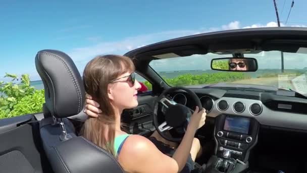Nahaufnahme: Glückliche Frau mit Wind im Haar fährt Cabrio am Strand entlang — Stockvideo