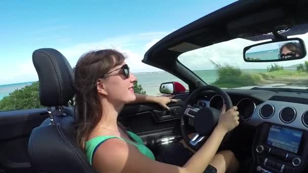 Nahaufnahme: junge Frau mit Wind im Haar fährt Cabrio am Strand entlang — Stockvideo
