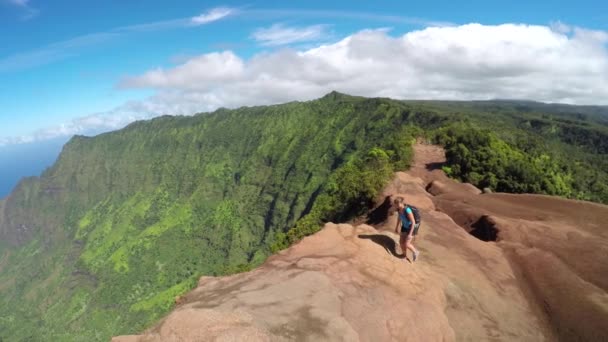 Активна молода жінка, що йде по високій гірській стежці з приголомшливим видом на океан — стокове відео