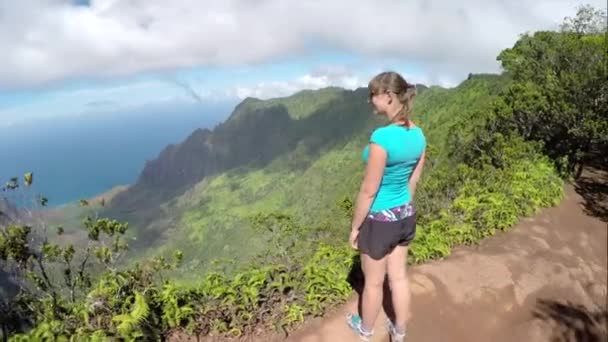 Leende kvinnlig vandrare på bergstopp beundra utsikt och pekar mot havet — Stockvideo