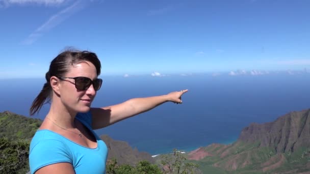 Lassú mozgás: mosolygó nő a hegy tetején felé mutat az óceán — Stock videók