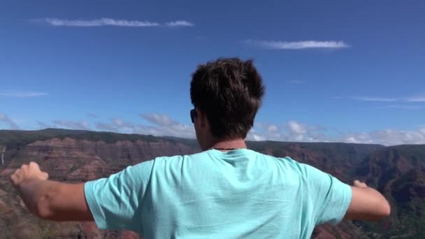 Pomalý pohyb: šťastný muž na vrcholu hory, který vítězně roztáhl paže — Stock video