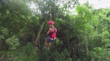 Young girl having fun while riding zipline cable forth and back