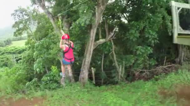 Jeune fille souriante glissant sur le câble au-dessus des verrières luxuriantes de la forêt tropicale de la jungle — Video