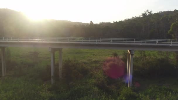 Luchtfoto close-up: witte Suv auto rijden over de brug over de groene moeras — Stockvideo