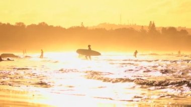 Ağır çekim: yüzme ve altın şafak sığ okyanus suda yürüyen insanlar