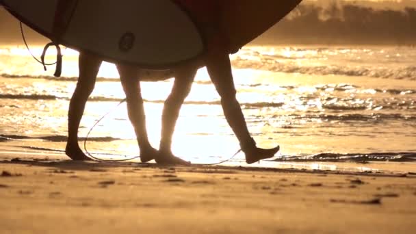 Zeitlupe aus nächster Nähe: Zwei Surfer laufen mit Surfbrettern am Strand entlang — Stockvideo