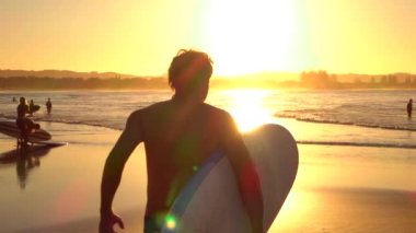 Ağır çekim: heyecanlı genç sörfçü elinde surfboard ile okyanusa çalıştıran