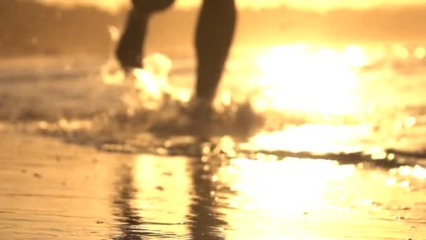 MOCIÓN LENTA: Joven trotando en aguas poco profundas al atardecer naranja — Vídeo de stock