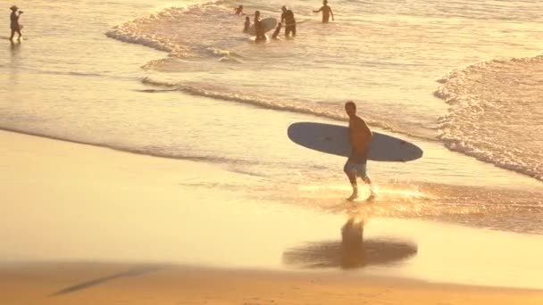 SLOW MOTION : Jeune surfeur excité courant avec une planche de surf dans les mains hors de l'océan — Video