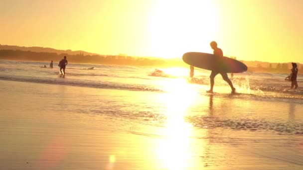 SLOW MIION: взволнованный молодой серфер бежит из моря с лонгбордом в руках — стоковое видео