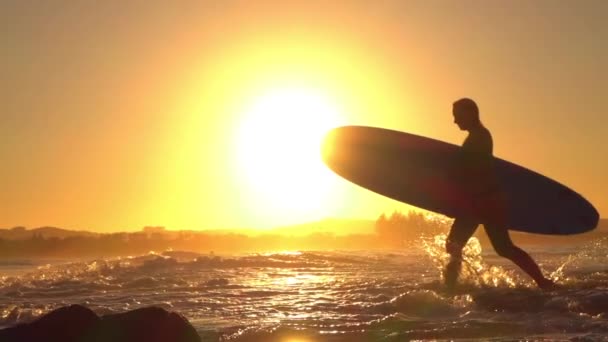 SLOW MOTION: Jovem surfista vindo de surf aventura com prancha de surf — Vídeo de Stock