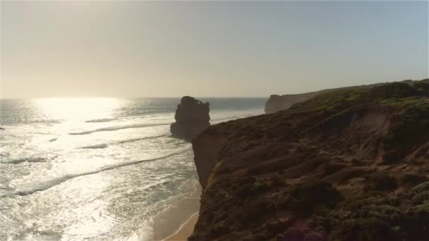 AERIAL: Flying above cliff towards sandstone wall rising from shallow water — Stock Video