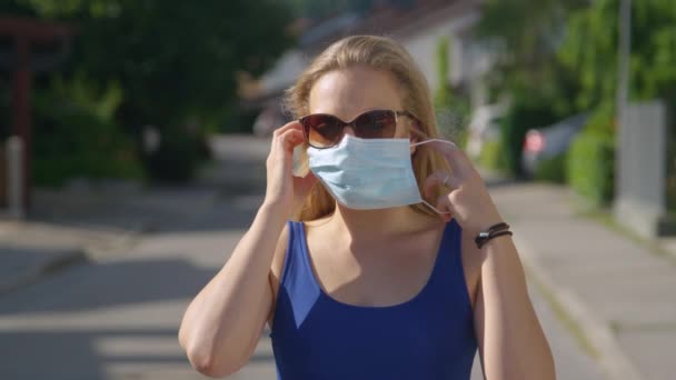PORTRAIT: Felelősségteljes nő napszemüveget visel felveszi a sebészeti arcpakolást. — Stock videók