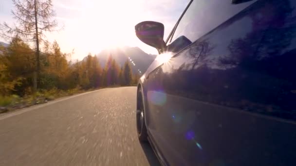 CERRAR: rayos de sol dorados reflejan fuera de la puerta de un coche de crucero por la carretera de montaña. — Vídeo de stock