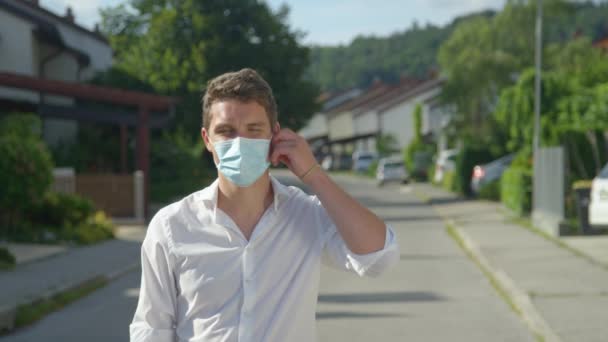 PORTRAIT: Guy standing in the middle of the street throws away his facemask. — Stock Video