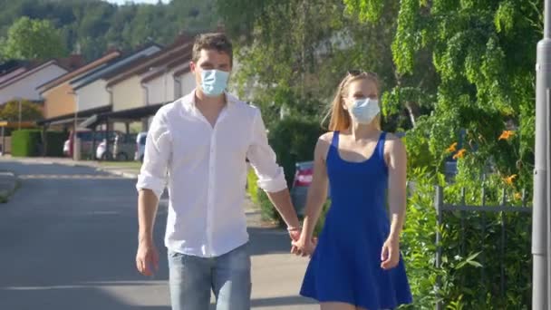 CLOSE UP: par kyssar samtidigt bär skyddande ansiktsmasker under sin promenad — Stockvideo