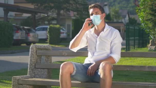 Irriterad man tar av sig sin medicinska mask medan han pratar i telefon. — Stockvideo