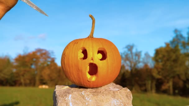 MOCIÓN LENTA: La calabaza de Halloween con la cara impactada es apuñalada con un cuchillo — Vídeo de stock