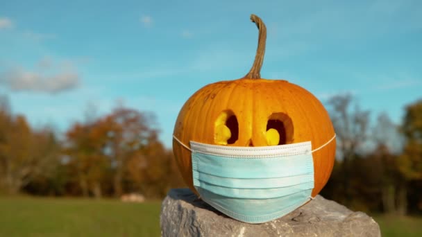 CLOSE UP: Gesneden Halloween pompoen met een gezichtsmasker als covid bescherming — Stockvideo