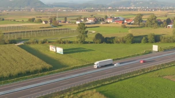 AERIAL: White semi truck hauls freight down a freeway crossing the countryside. — Stock Video