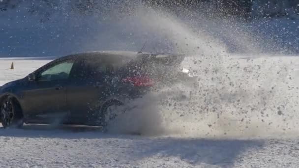 SLOW MOTION : Prise de vue cinématographique d'une voiture déchiquetant de la neige alors qu'elle court le long de la piste de ski. — Video