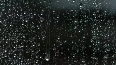 Yağmur damlası yaz fırtınası sırasında ıslak bir pencereden aşağı damlar..