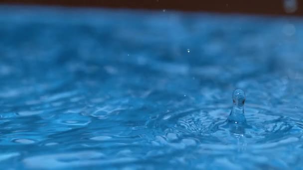 MACRO: Краплі дощу починають падати в басейн на початку шторму . — стокове відео