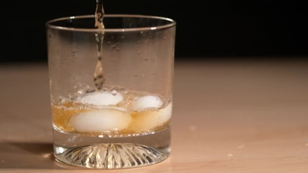 CLOSE UP: Smaklig whisky hälls över isen inuti ett elegant glas. — Stockvideo