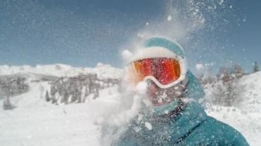 Mutlu kadın snowboardcu yüzüne şişkin bir kartopuyla vuruluyor..