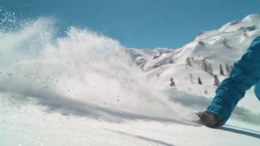 Snowboardcu patikadan ayrılırken elini toz kar üzerinde sürüklüyor..
