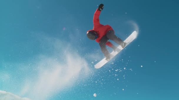 CERRAR: snowboarder extremo hace un truco de aire grande girando fresco en un día soleado. — Vídeos de Stock