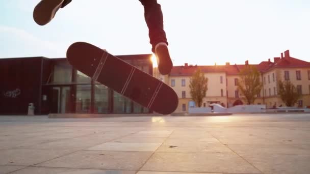 LOW ANGLE: Unerkennbarer Skater macht einen Flip-Trick, während er um einen Platz reitet. — Stockvideo