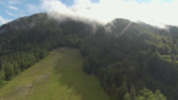 AERIAL: Vliegen over lege skipistes van Kranjska Gora als de mist stijgt uit het bos — Stockvideo